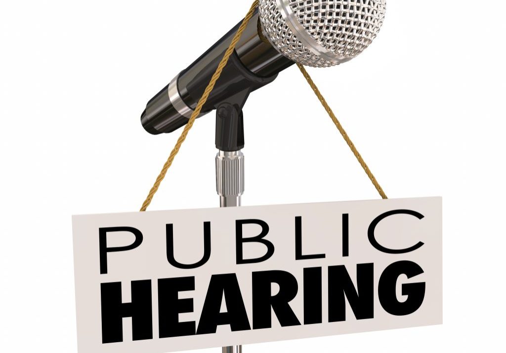 Public Hearing words on sign around a microphone to illustrate feedback, input, opinion or information sharing during a government or association meeting