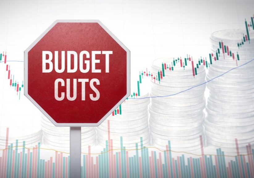 Budget cuts sign with financial graphs and stacked coins, representing reduction in government spending and economic measures, finance austerity concept, economic pressure, financial limitation